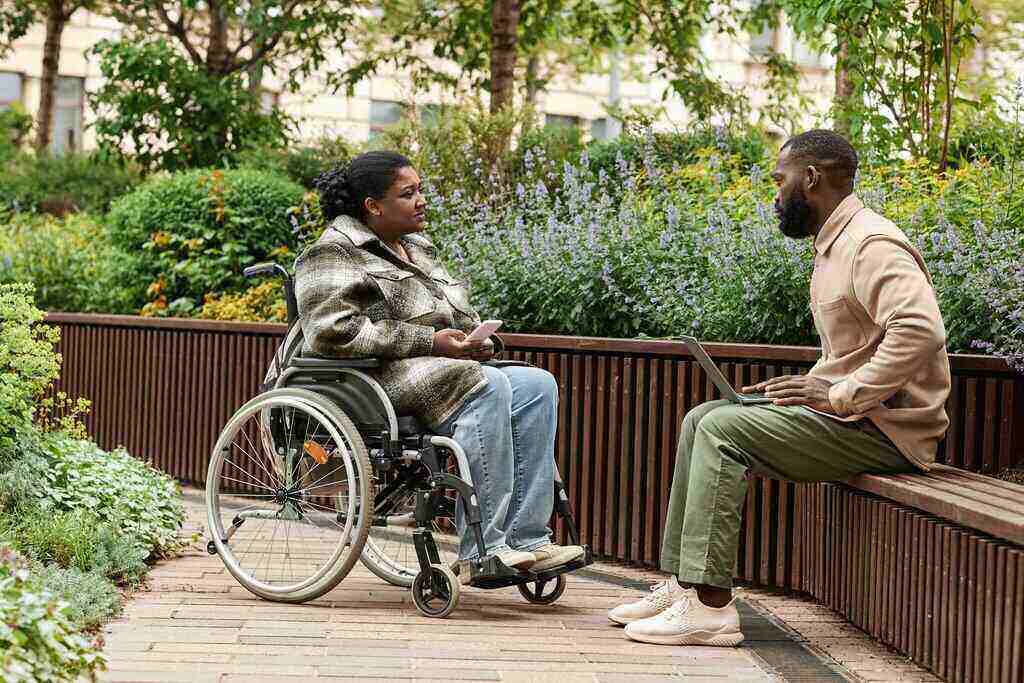 Disabled woman in wheelchair sitting outside with support worker