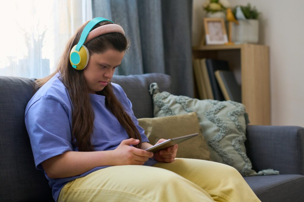 Young female with disability watching online video or movie in living room