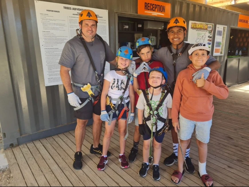 Group of friends in harnesses as tree climbing activity