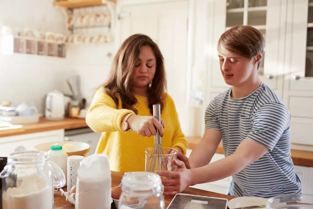 Two disabled friends with down syndrome cooking in kitchen
